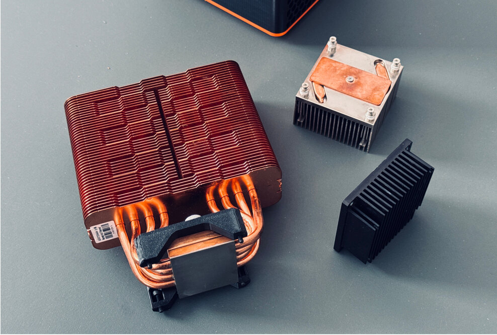 Standard cooler, prototype cooler, and 1.5 kg cooper heat sink for the Bitaxe GT.